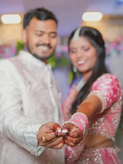 A happy, candid shot of the couple showing off their rings to the camera. Their joyful expressions and connected hands tell a story of excitement and love during their engagement ceremony.