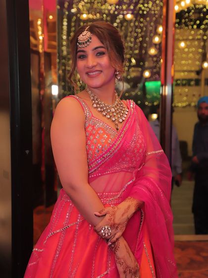 Posing for a photo at the wedding. The combination of a sleeveless blouse, statement jewelry, and a bright, happy color palette creates a look that is both traditional and modern.