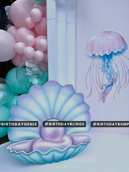 A pearlescent seashell and jellyfish cutout, adding to the magical underwater atmosphere.