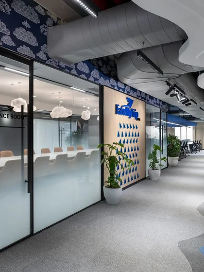 The hallway view into the conference room reveals how the space integrates with the rest of the office. Glass walls maintain a sense of openness, while frosted lower panels provide privacy for meetings.