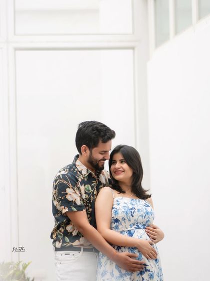 A happy couple's portrait from a maternity shoot. The floral patterns on their outfits add a fresh and cheerful feel.