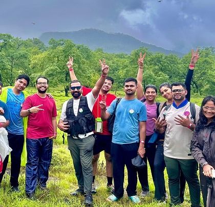 Another happy group celebrating the completion of the Dudhsagar trek, with the lush green hills of the Western Ghats behind them.