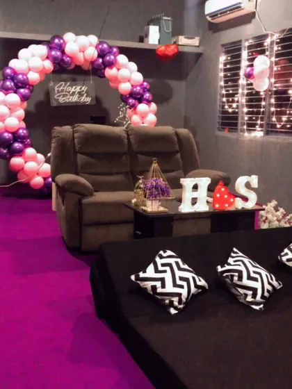 A full view of one of our standard birthday decoration packages. It includes a balloon arch, a 'Happy Birthday' sign, and personalized initial lighting, all set up in a cozy, private room.