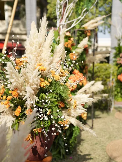 A detailed shot of a floral arrangement, showing the beautiful textures of pampas grass and marigolds. These elements are perfect for creating a warm, autumnal feel.