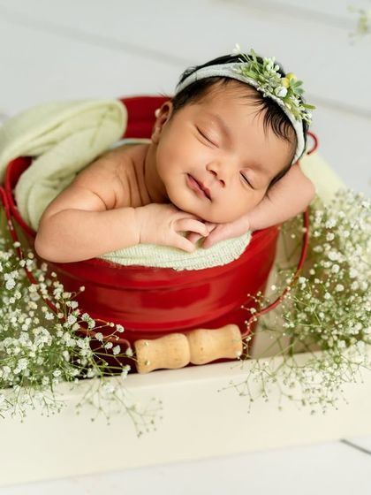 A portrait capturing the baby's delicate features as she rests her chin on her hands. The soft lighting and floral elements create a feeling of pure serenity.