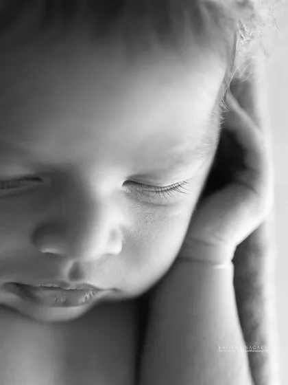 A close-up of a newborn's face in black and white. This style strips everything away until all that's left is the truth and emotion of the moment.