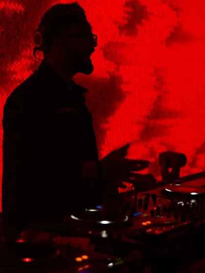 Late night sessions. A silhouette of me against the red lights of the DJ booth, completely absorbed in the music.