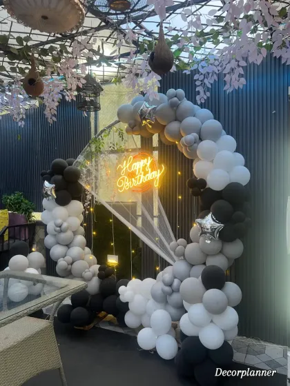 A side view of the sophisticated black and white balloon arch, showing how it beautifully integrates with the cafe's decor. The hanging cherry blossoms at the venue add an extra layer of charm to the overall look.