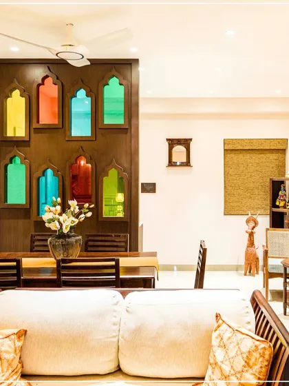 A dining area partition made of jharokha-style arches with colorful stained glass, blending Rajasthani and Bengali craft.