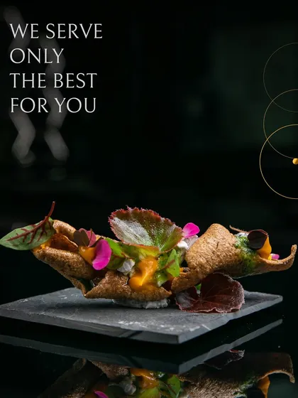We serve only the best. This appetizer features a crispy, cone-shaped shell filled with a vibrant mixture and garnished with edible flowers and microgreens, served on a modern slate platter.