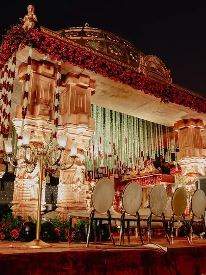 A nighttime view of the temple-style mandap, illuminated to highlight its intricate carvings and architectural details, creating a dramatic and regal presence.