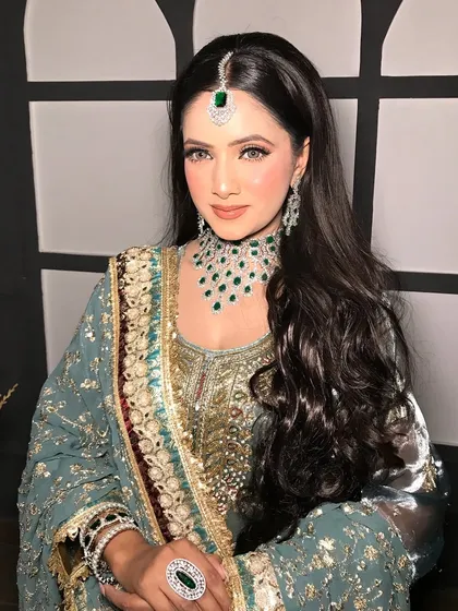A frontal view, her sleek hair parted in the middle to show off the maang tikka.