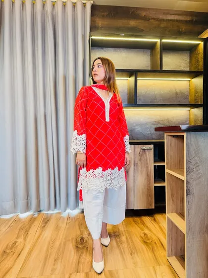 The side profile of this red and white suit highlights the beautiful lace detailing on the bell sleeves. It's a modern touch that adds style and comfort to a traditional outfit.