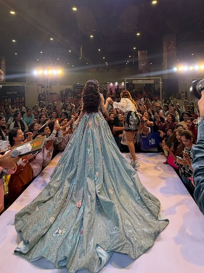 Adjusting the model's gown on the runway. A true artist takes care of the entire presentation, not just the makeup.