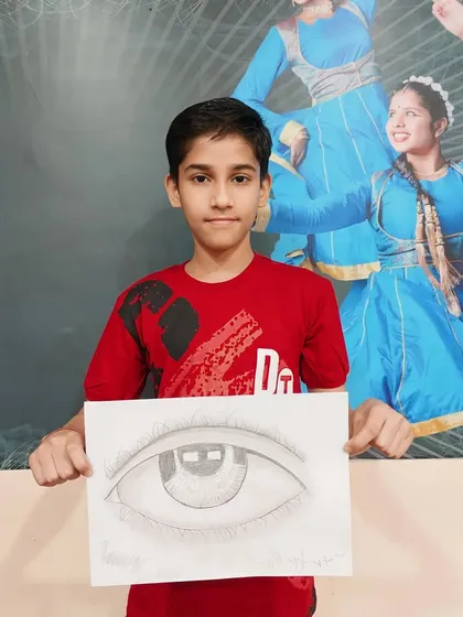 Learning to draw realistic features is a key skill. This student proudly displays his detailed pencil sketch of an eye, showcasing his understanding of shading and form.