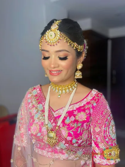 Pooja's smile shows her happiness with her final look. The makeup is perfectly balanced with her ornate jewelry and vibrant outfit.