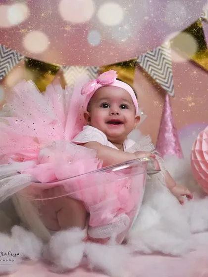 A dreamy, magical setup for a baby girl's photoshoot. With a pink and gold theme, fluffy clouds, and twinkling lights, this portrait feels like it's straight out of a fairytale.