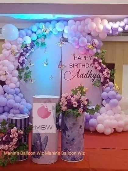 An elegant butterfly-themed party in shades of lavender and lilac. The design includes arched backdrops, floral arrangements, and custom-printed pedestals for a cohesive and beautiful look.