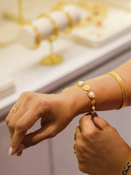 The beauty is in the details. A client tries on a delicate gold-plated bracelet at our Hyderabad store, experiencing the fine craftsmanship and comfortable elegance of our designs firsthand.