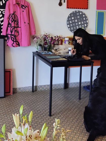 A quiet moment of creation in the studio, with my dog Kai watching over me. The space is filled with art, from paintings to a custom-painted jacket, showing that art is in everything.