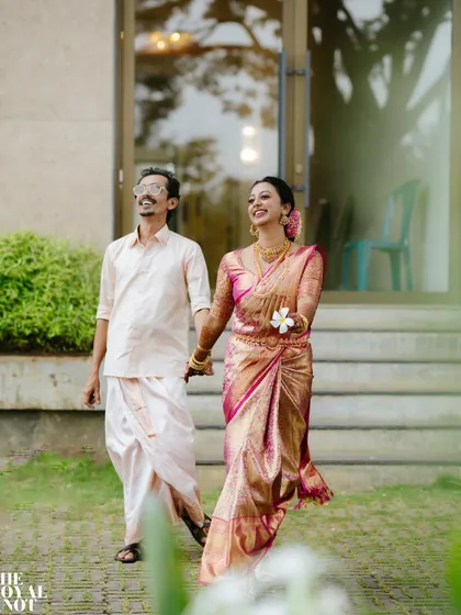 A candid shot of the newly married couple. The bride's pink Kanchipuram silk saree looks flawless even as she walks, showcasing the security of my drape.