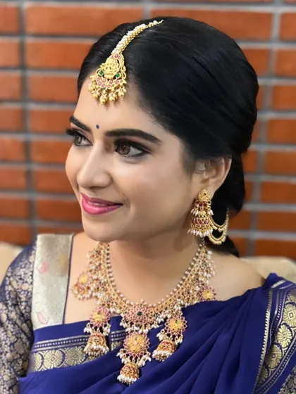 A closer look at a classic Muhurtham style. The focus here is on clean, defined eyes and a soft lip color that complements the royal blue saree. The elegant bun and traditional maang tikka complete this timeless South Indian bridal look.