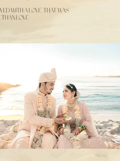 A serene moment from a beach wedding in pastel tones. The couple shares a traditional ritual moment while sitting on the sand.