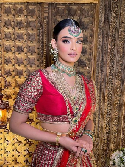 A classic red and green bridal combination. The makeup is kept timeless, with a focus on a radiant complexion and defined eyes to complement the traditional colours.