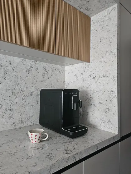 This coffee corner, with its beautiful quartz continuing up the wall, is a perfect example of how a simple, functional space can also be a design moment. The fluted wood cabinets above add a layer of texture.