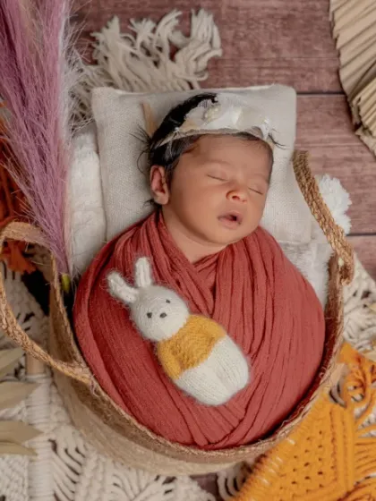 A boho baby. This creative setup uses a hanging basket, macrame, and dried foliage to create a trendy and artistic newborn portrait.