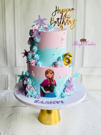 A magical two-tier Frozen cake for Saanvi's 6th birthday. The pink and blue ombre design is decorated with sparkling snowflakes and features the beloved Princess Anna.