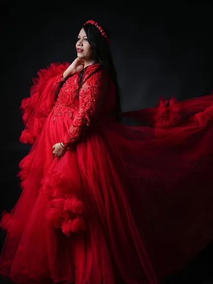 For a bold and dramatic statement, our vibrant red tulle gown is a stunning choice. Set against a simple black backdrop, the color and texture of the dress make for a powerful and unforgettable solo maternity portrait.