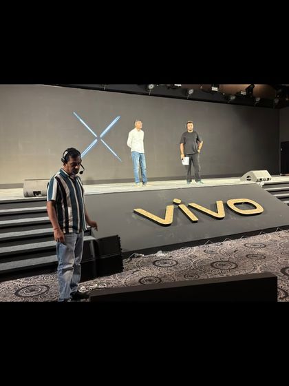 A team member with a headset on stage during the Vivo launch rehearsal, overseeing the setup.