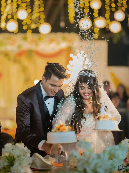 The cake cutting ceremony at a Catholic wedding reception, with confetti adding to the festive and celebratory atmosphere.
