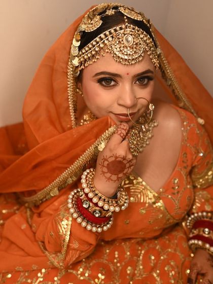 A bright and cheerful orange lehenga with gold embroidery. The look is completed with a traditional sheesh patti and a heavy kundan choker.