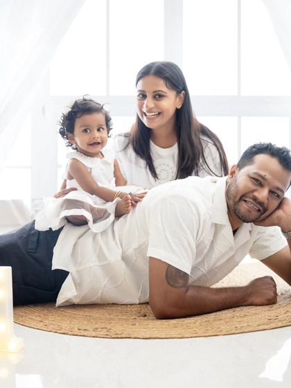 A playful family moment celebrating their daughter's first birthday. The baby is having fun sitting on her dad's back.