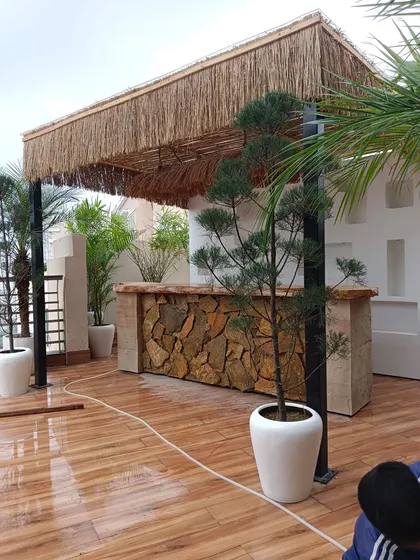 Your terrace can be the perfect spot for a party. Here, we built a custom outdoor bar with a natural stone facade and a rustic thatched-roof pergola, creating a resort-like vibe right at home.