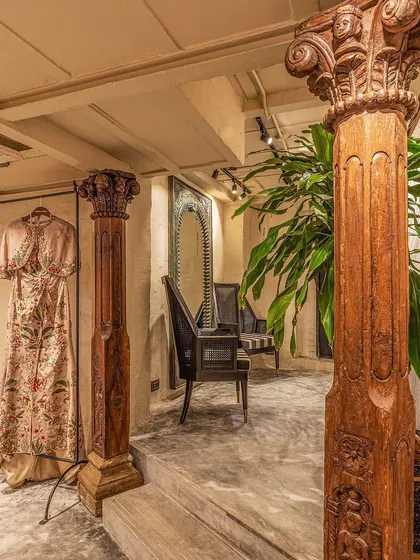 We believe in celebrating materiality and heritage. These graceful vintage wooden columns, salvaged and restored, define the entrance to the changing rooms. They stand against matte greige hand-plastered walls, showcasing our signature blend of raw textures and refined historical elements.