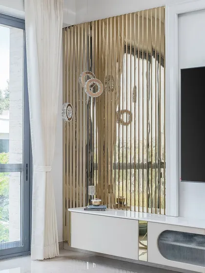 A detail shot of the TV unit area, where a fluted, reflective gold panel creates a stunning play of light and texture. This is how we add a touch of glamour to functional pieces.
