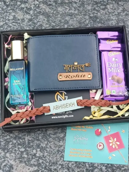 Celebrate Rakhi with this thoughtful hamper containing a personalized blue leather wallet, a braided leather rakhi, perfume, and Dairy Milk chocolates.