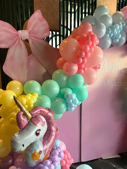 The top of the balloon arch is adorned with a large, pretty pink bow, completing the whimsical look.
