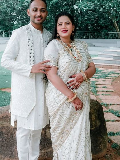 A beautiful couple dressed in coordinated white traditional outfits for their twin babies' naming ceremony.