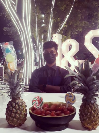 Fun and creative serving ideas for a wedding event. Here, we've set up a station with melon ball vodka shots and colorful lollipops, displayed on pineapples for a playful and tropical touch.