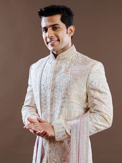 A moment of quiet confidence. This groom wears a pastel-toned sherwani with delicate, multi-hued embroidery, representing a softer, more romantic approach to wedding day attire.
