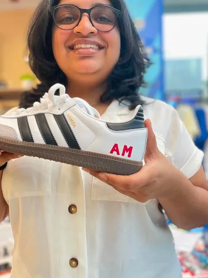 A happy customer showing off her freshly personalized Adidas Sambas. A simple, clean monogram is a popular choice for adding a unique and personal touch to brand new kicks.