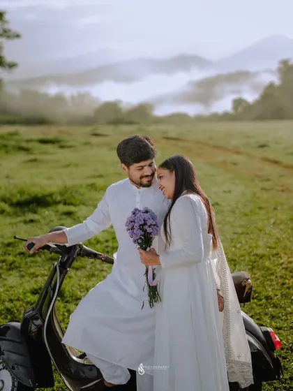 A happy, candid moment by the scooter. The misty hills in the background create a dreamy and atmospheric setting.