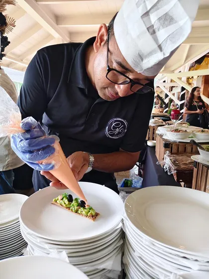 A member of our talented team carefully piping a sauce onto an appetizer at the Bombay Gymkhana event. It's all about teamwork and precision.