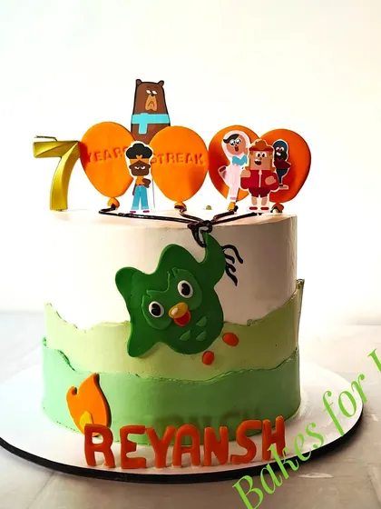 A fun Duolingo-themed cake celebrating a 7-year learning streak. The cake features the green Duolingo owl and other characters from the language-learning app.