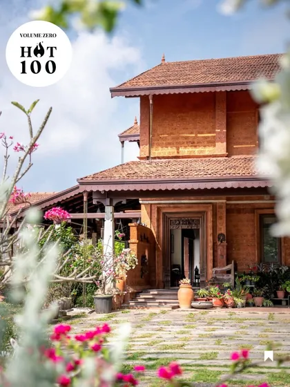 Framed by flowers, the entrance to the Varadarajan House is a composition of natural materials and traditional forms. The laterite stone walls and carved wooden door create a sense of arrival that is grounded and authentic to its location.