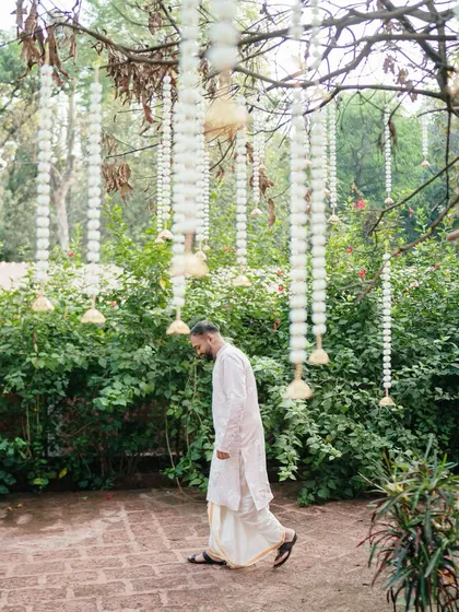 A candid shot of the groom walking through the garden. This image captures a moment of quiet contemplation amidst the beautiful, festive decor.